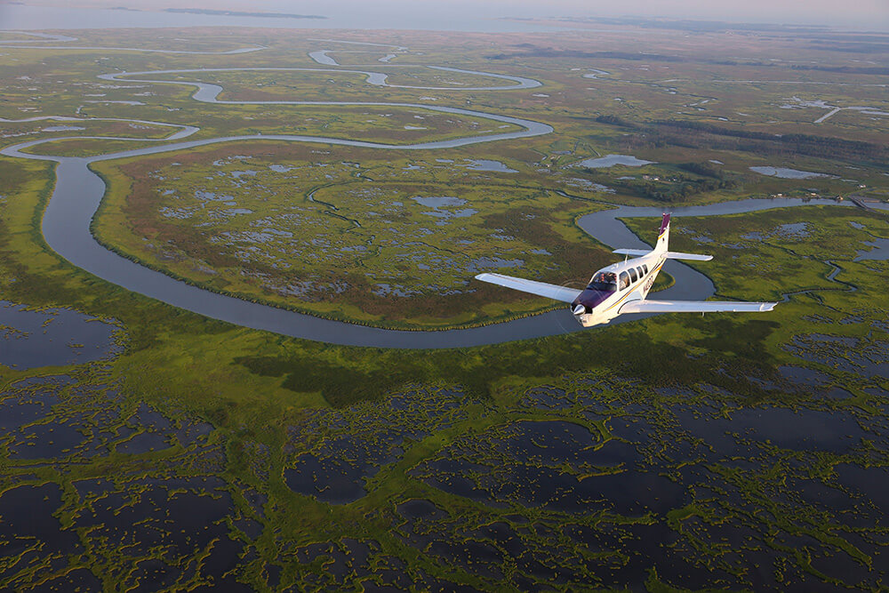 An aircraft flying over marshy terrain